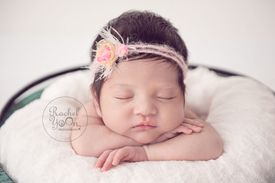 newborn baby girl with a pink flower headband in a basket - newborn photography vancouver