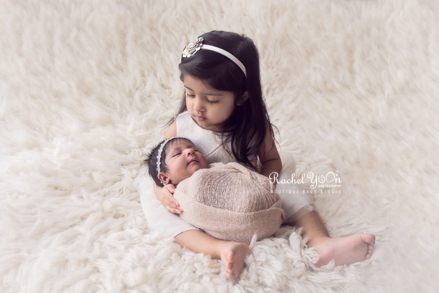 sister holding her baby sister - newborn photography vancouver
