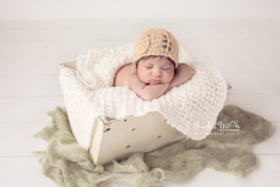 newborn baby girl wearing a bonnet in a basket - newborn photography vancouver