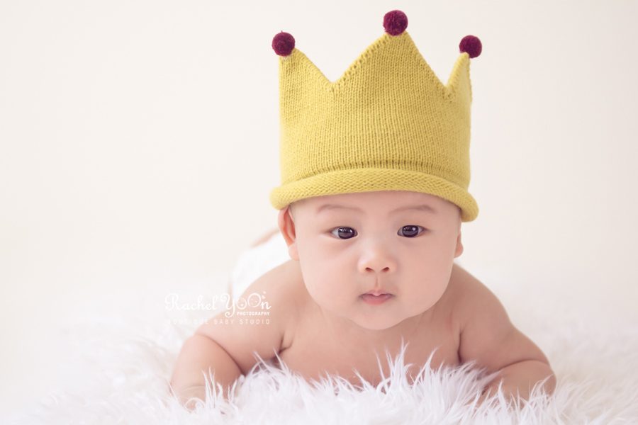 baby with a yellow crown hat doing tummy time - Vancouver Baby Photography for 100 days