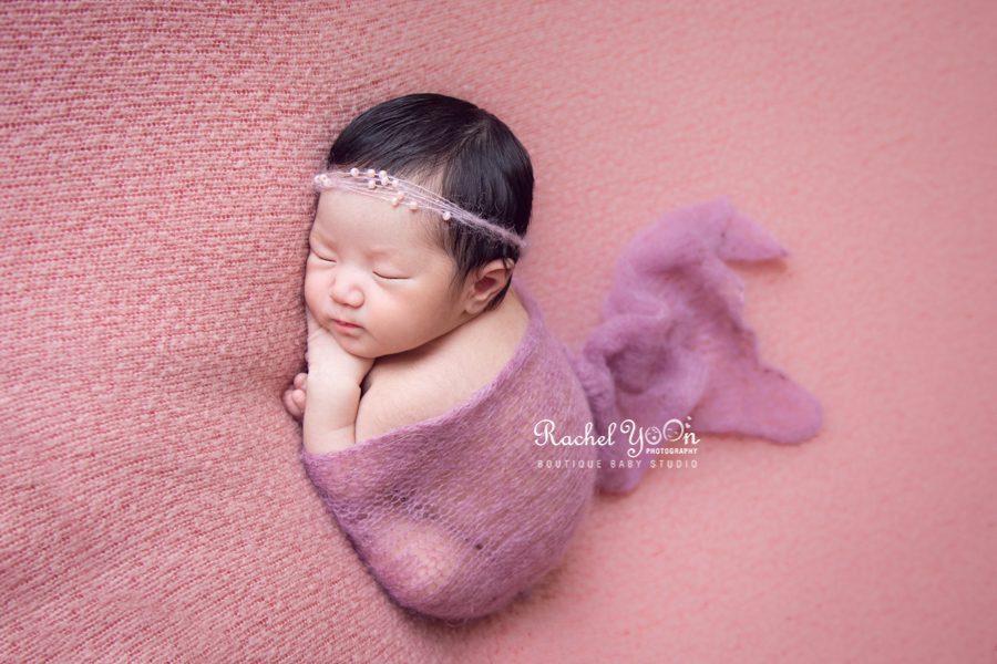 newborn baby wrapped in purple in taco pose