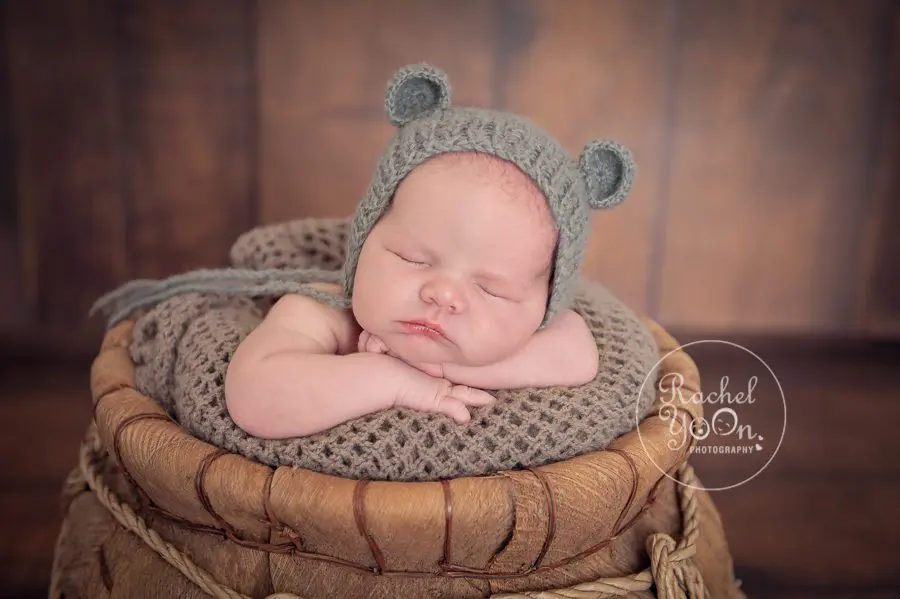 newborn baby boy in a basket with a bear hat - newborn photography vancouver
