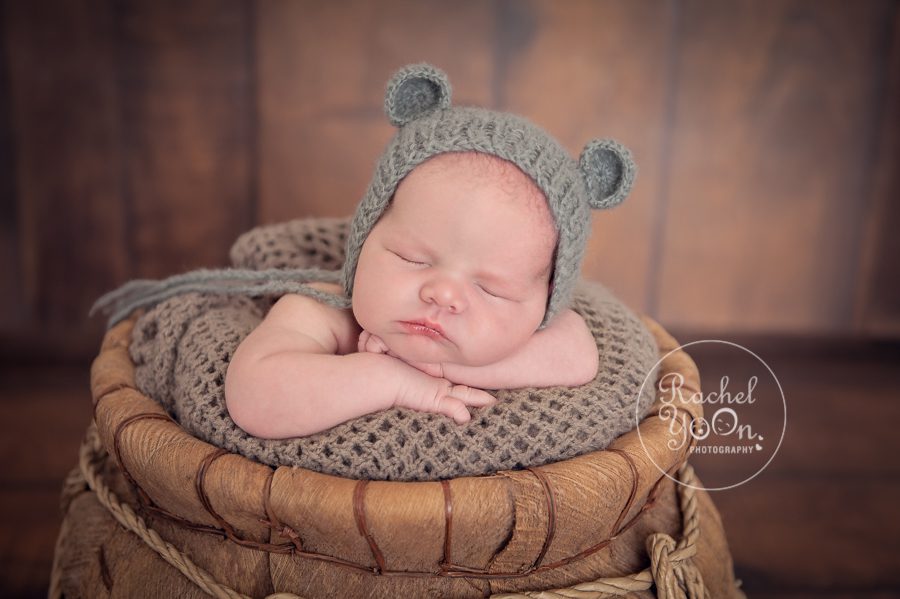 newborn baby boy in a basket with a bear hat - newborn photography vancouver