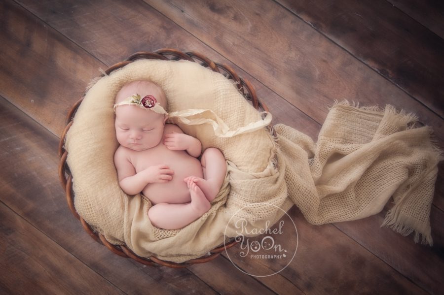 newborn baby girl lying in a brown basket - newborn photography vancouver