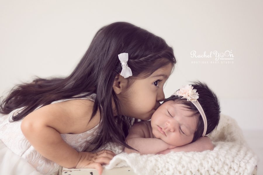 sister kissing her newborn baby sister - newborn photography vancouver
