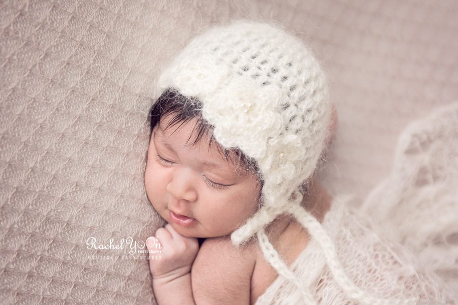 close up of a newborn baby girl with a white bonnet - newborn photography vancouver