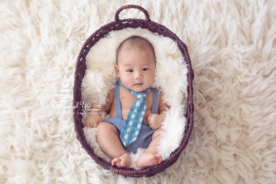 baby with a blue tie lying in a basket - Vancouver Baby Photography for 100 days
