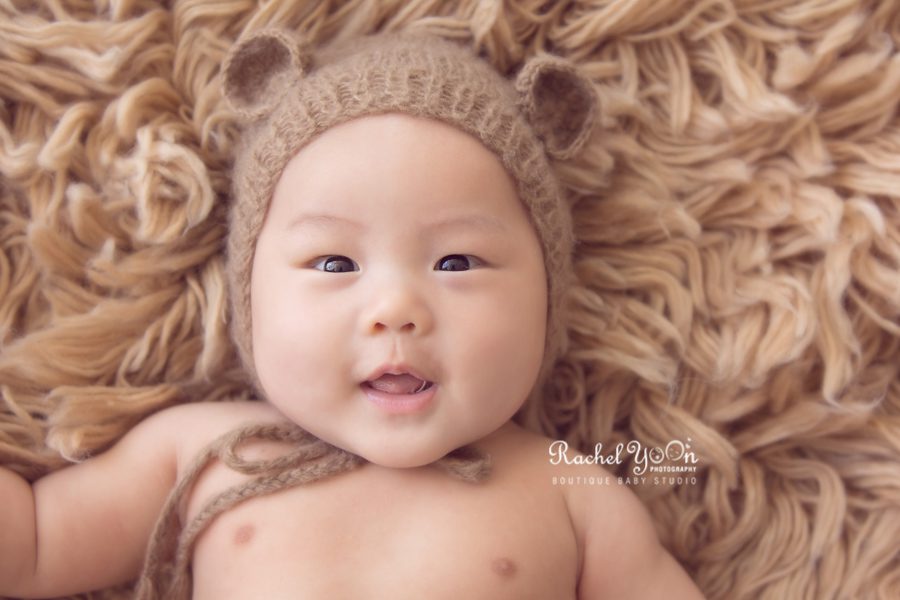 baby boy with a brown bear hat on a rug - Vancouver Baby Photography for 100 days