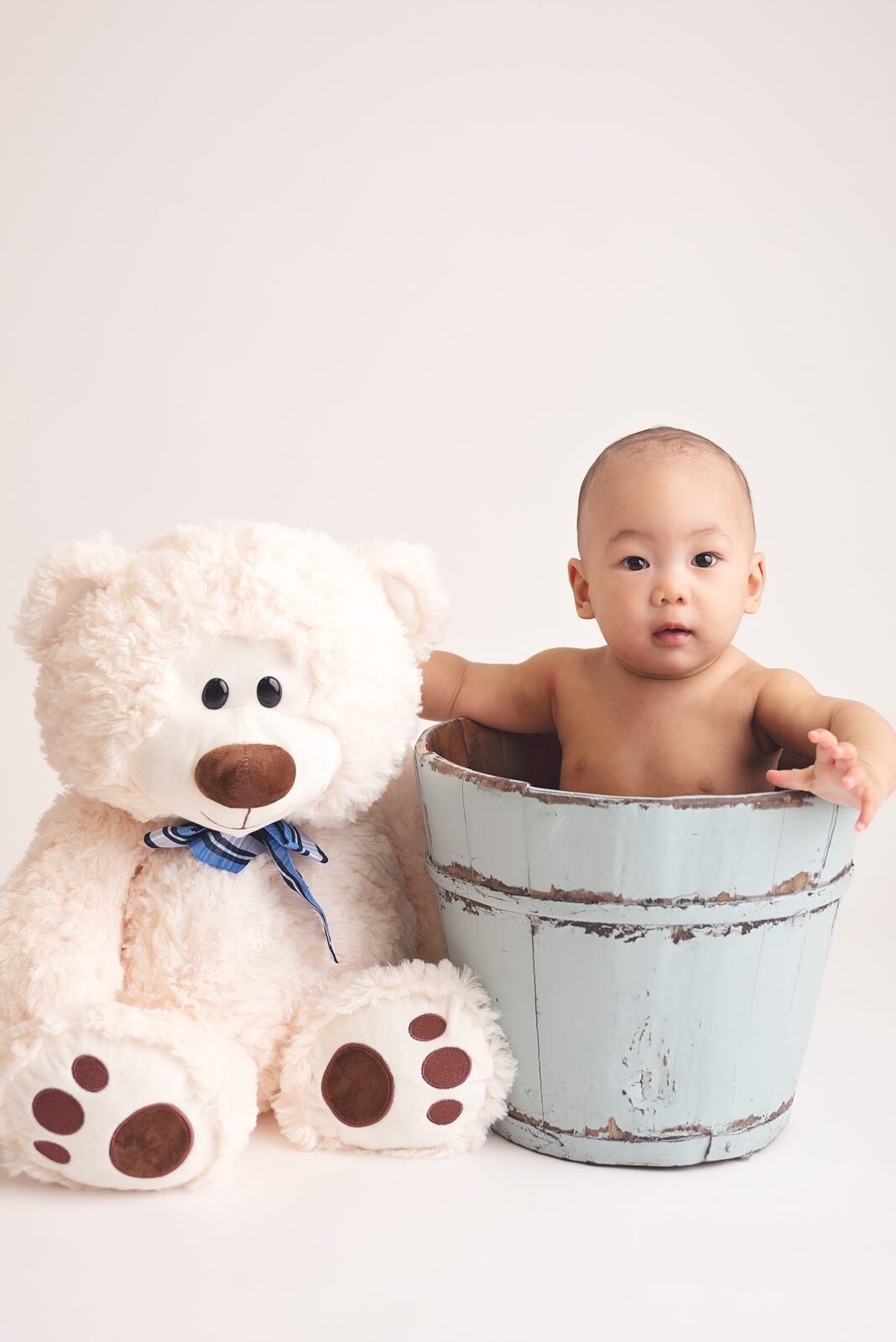 baby sitting in a bucket with teddy bear