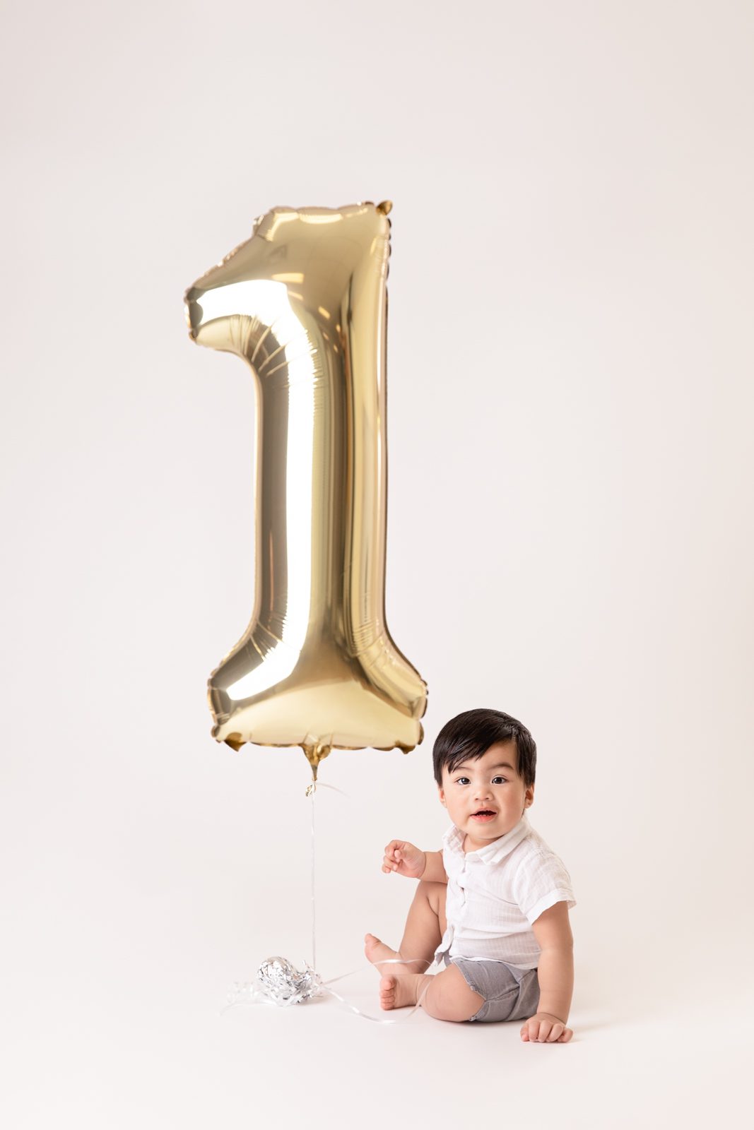 baby boy holding '1' balloon