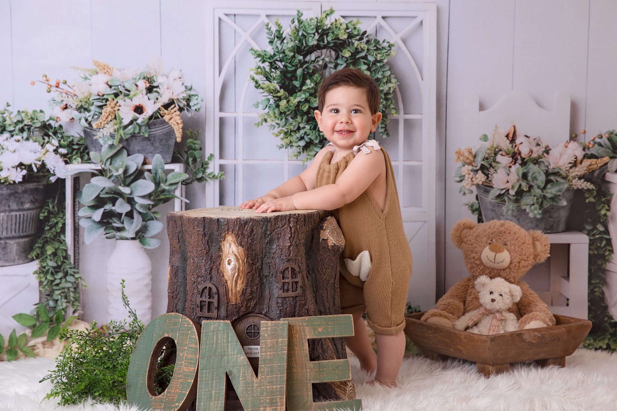 baby boy standing next to a log with one sign